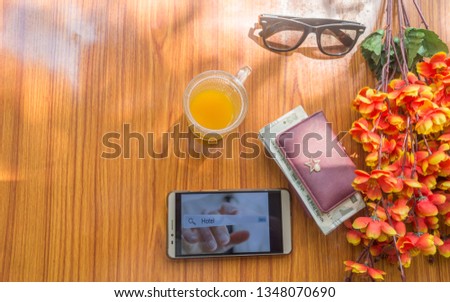 Close-up Of screen interface of booking hotels using cell phone along with travel accessories. Book a room in holiday Concept. Summer time background with natural sun light. Copy space for text on le