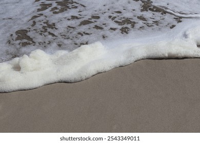 Close-Up of Sea Foam Gently Resting on Sandy Beach - Powered by Shutterstock