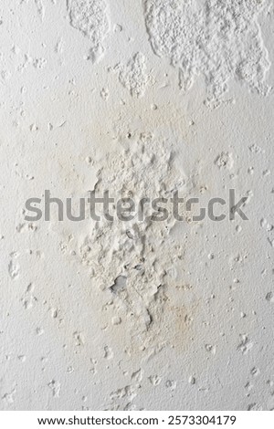 close-up section of plaster finished wall surface with damage caused by moisture, peeling or flaking off with cracks, chips and water penetrated and stained