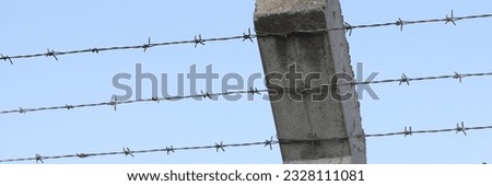 Close-up of security barbedwire fence, wire with clusters of short, sharp spikes on concrete pillar. Fence or warfare obstruction, correctional institution concept