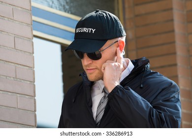 Close-up Of Security Guard Standing In Front Of The Entrance Listening To Earpiece