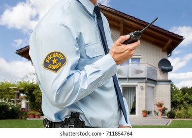 Close-up Of Security Guard Standing In Front Of Their House Holding Walkie Talkie