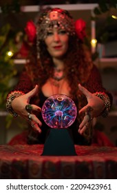 Close-up Of A Seer's Hands Around Her Fortune-telling Crystal Ball With Lightning Bolts Inside With The Gypsy Woman Out Of Focus In The Background