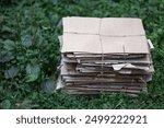 Close-up selective focus cardboard for recycling waste paper on a green background. Secondary raw materials. Paper recycling business. Corrugated material curved corrugation laid two layers cardboard