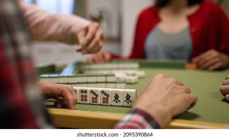 closeup with selective focus of a hand tapping on the table while waiting for his turn at gambling table. asian traditional strategy game concept. words on mahjong tile translation: east - Shutterstock ID 2095390864