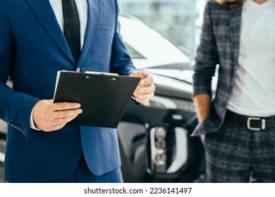 Close-up and selective focus a human's hand with tablet blurred background of car in showroom. Business and transportation concept. - Shutterstock ID 2236141497