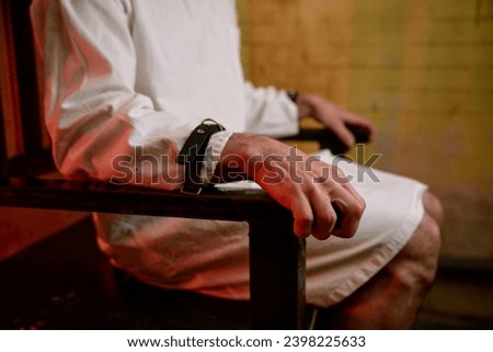 Closeup selective focus on hands of crazy man bound with belt to chair