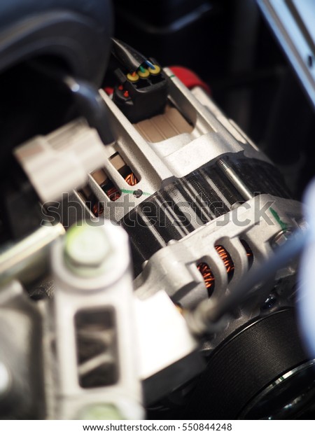 close-up selective focus on small eco-car new electrical\
 power alternator motor voltage generator installed with driving\
belt and electric plug and wiring under the hood of gasoline car\
engine 