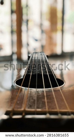 Close-up selective focus view of acoustic guitar strings and fretboard leading toward the headstock.