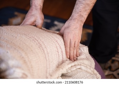 Closeup selective focus view on the hands of a therapist performing petrissage, or kneading technique, on the sacroiliac joints of female patient.