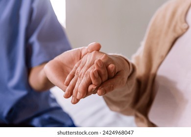 Close-up senior Asian woman hand with her caregiver helping hands, Caregiver visit at home. Home health care and nursing home concept. - Powered by Shutterstock