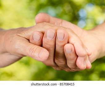 Closeup of senior couple hands holding together outdoors.
