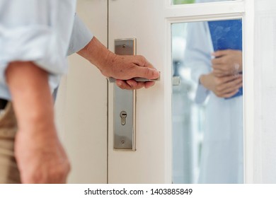 Close-up Of Senior Man Holding Door Handle And Opening The Door Of His House To The Doctor