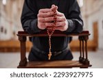Close-up of senior man with rosary beads praying standing behind the altar in church