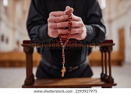 Close-up of senior man with rosary beads praying standing behind the altar in church