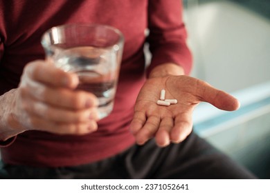 Close-Up of a Senior man taking his medication in the bathroom at home - Powered by Shutterstock