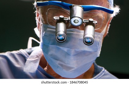 A Closeup Of Senior Surgeon Performing An Operation While Looking Through An Advanced Surgical Loupe In A Modern Operating Room