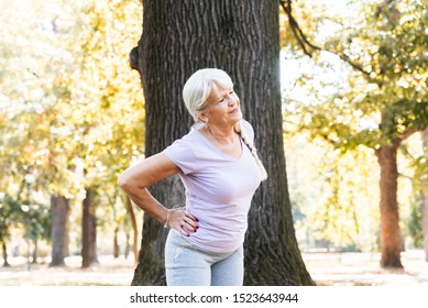 Closeup Of Senior Woman Doing Fitness Workout In Park. Hip Stretching Position. Painfull Expresion Of Her Face. Billboard Image