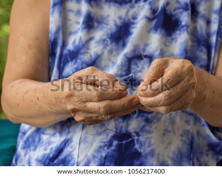 Close-up of senior woman hands trying to thread a needle