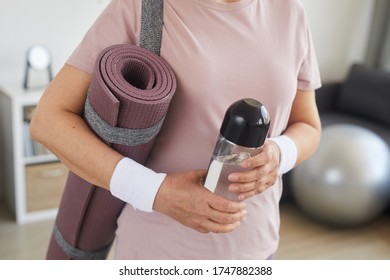 Close-up of senior woman holding exercise mat and bottle of water she is ready for sports training