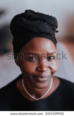 Close-up of a serene African woman in black with a headwrap, subtle smile