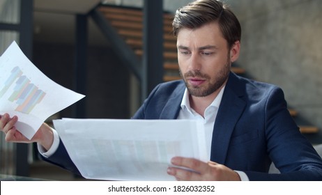 Closeup Serious Businessman Looking On Diagram In Office. Focused Man Reading Documents In Home Office. Handsome Business Man Making Notes In Notepad At Workplace In Slow Motion.