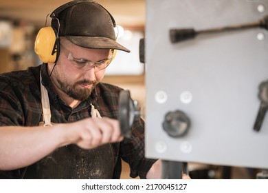 Closeup Serious And Concentrated Man Worker, Carpenter In Protective Coverall, Glasses, Headphones Work With Grinder Saw