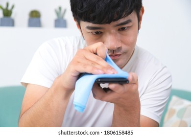 Closeup Of Serious Man Cleaning Phone Screen By Sanitizer.