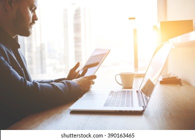 Closeup of a serious man office worker is reading world news in internet on touch pad, while is sitting at the table with open net-book. Closely of a successful male lawyer is using digital tablet