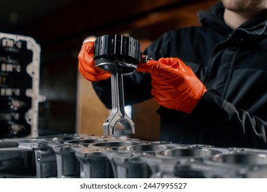 close-up At a service station on the table young engine repairman puts a piston part in place - Powered by Shutterstock