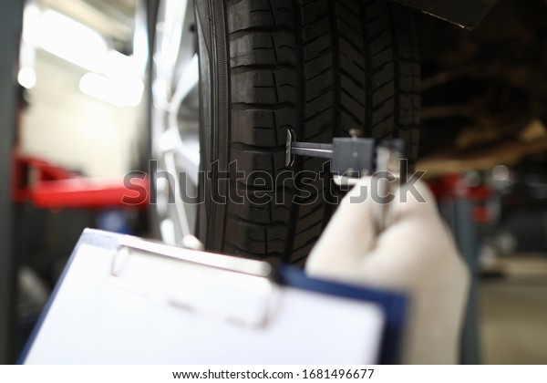 Close-up of service station worker\
making diagnostic of automobile damaged. Special instrument for\
wheel. Car maintenance concept. Vehicle restoration\
workshop