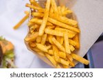 Closeup of a serving of of crispy golden French fries on a restaurant table. A perfect snack or side dish for any fast food meal. Dining out. Fried potato texture. Copy space