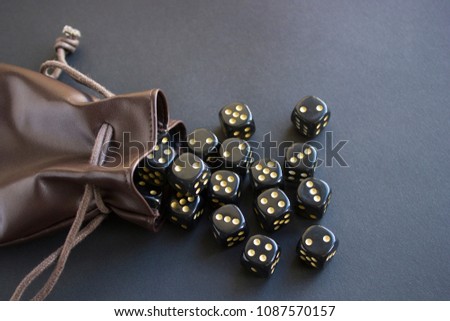 Close-up set of gaming dice rolled out of leather bag on dark background. Concept with copy space for games. Top view. 