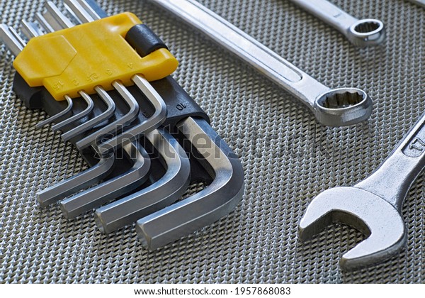 Closeup of a set of open-end wrenches\
in hex keys for maintenance on a steel\
background.