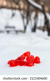 Closeup set of small bright red glass hearts on powdery snow of snowdrift at cold winter day in park, symbol of romantic love, St. Valentine's Day holiday concept, vertical image with low angle shoot