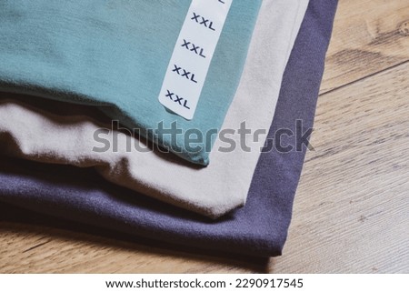 Close-up of a set of XXL size T-shirts on wooden floor. Selective focus.