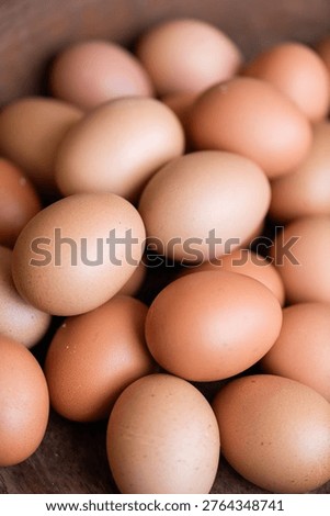 A close-up of several brown eggs, showcasing their smooth texture and natural color, arranged in a rustic wooden setting.