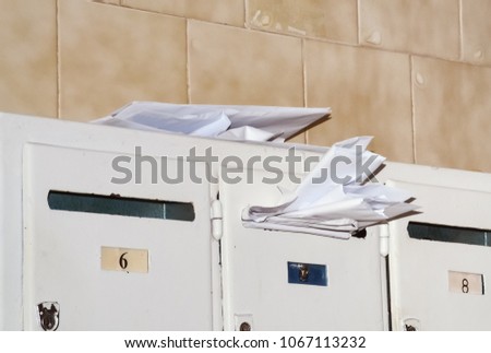 Closeup of several letter boxes one of which is full of bills and letters