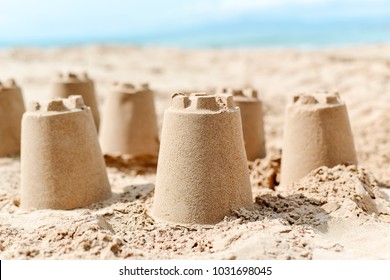 closeup of several sandcastles on the sand of a beach, with the sea in the background