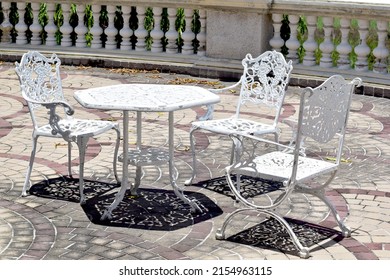 Close-up of Several white wrought iron chairs and a white wrought iron table with the reflection of the sun on the balcony of a luxury building in Thailand.