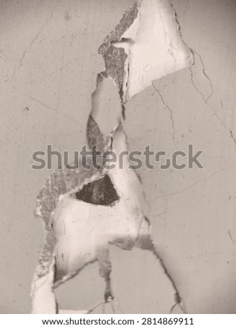 Close-up of a severely damaged and deteriorating wall with large sections of paint peeling off, revealing a rough, darker texture underneath and visible cracks
