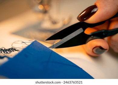 close-up in a sewing workshop scissors for working on fabric cut off blue thread