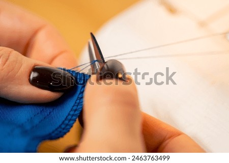 close-up in a sewing workshop scissors for working on fabric cut off blue thread