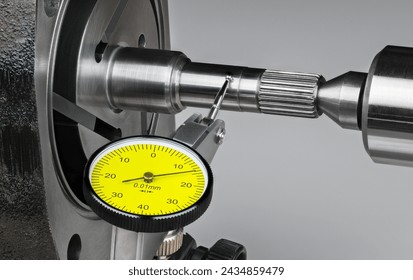 Closeup a shaft run-out measurement by yellow dial test indicator with metal probe on hinge and round tip. Precise mechanical tool at measuring runout of steel rotor of rotary vane compressor of pump.