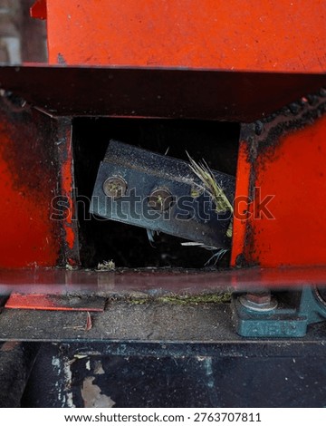 Close-up of sharp cutting blade inside a grass chopper machine, agricultural equipment detail with industrial metal texture.