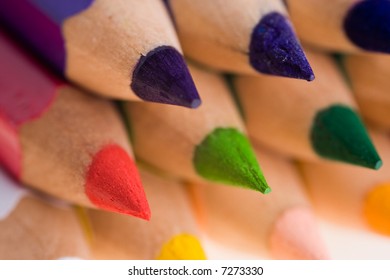 A closeup of the sharpened tips of wooden colored pencils with a narrow depth of field and the focus on the first pencil.