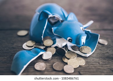 Closeup Of Shattered Broken Piggy Bank With Coins On Rustic Wooden Table