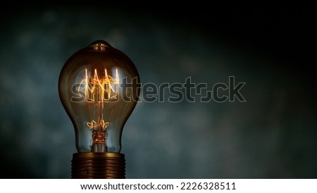 Close-up of shining light bulb, dark background