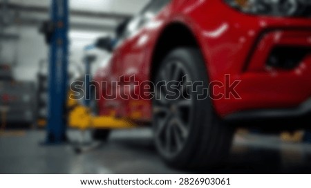 Close-up of a shiny red car elevated on a hydraulic lift in a clean, well-lit automotive service center.
