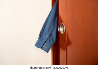 A Closeup Of A Shirt Sleeve Stuck In Between The Wardrobe Door In A Room